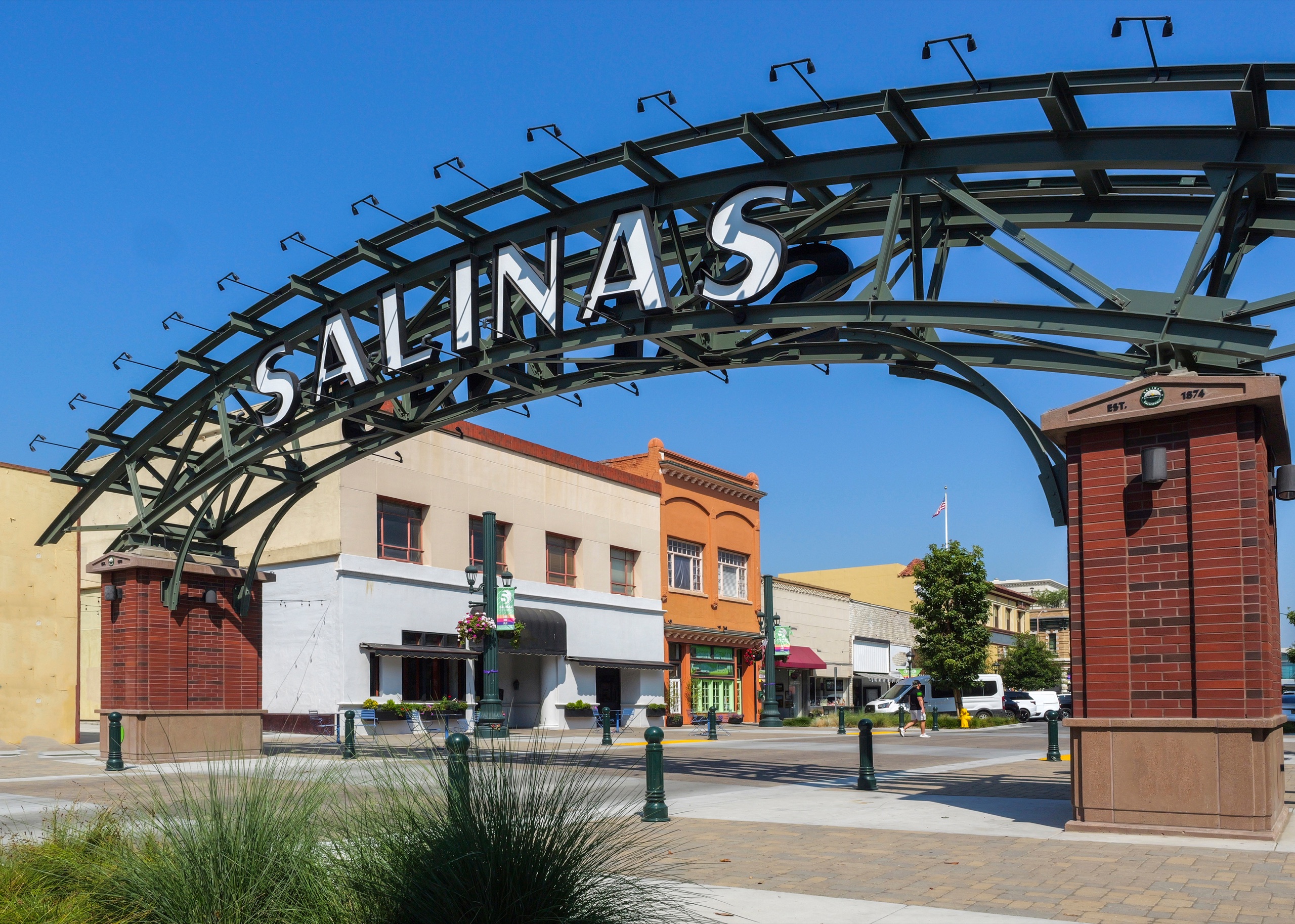 The SALINAS gateway arch and downtown storefronts beneath a clear blue sky in Salinas, California